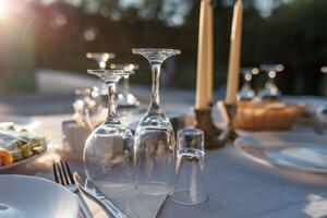 empty wine glasses on banquet served table in open air in rays of setting sun photo