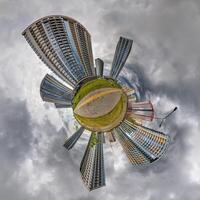 abstract swirling tiny planet spherical panorama of multi-storey buildings of skyscrapers of a residential complex in the form of a butterfly, bugs, crabs in sky with clouds photo