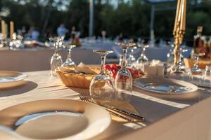 empty wine glasses on banquet served table in open air in rays of setting sun photo