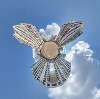 abstract swirling tiny planet spherical panorama of multi-storey buildings of skyscrapers of a residential complex in the form of a butterfly, bugs, crabs in sky with clouds photo