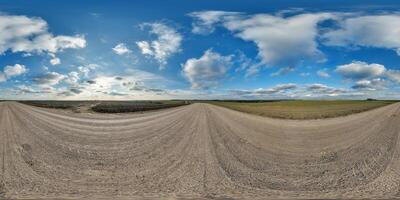 hdri 360 panorama on gravel road among fields in spring evening with awesome clouds in equirectangular full seamless spherical projection, for VR AR virtual reality content photo