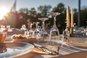 empty wine glasses on banquet served table in open air in rays of setting sun photo