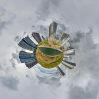 abstract swirling tiny planet spherical panorama of multi-storey buildings of skyscrapers of a residential complex in the form of a butterfly, bugs, crabs in sky with clouds photo