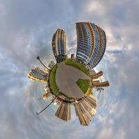 abstract swirling tiny planet spherical panorama of multi-storey buildings of skyscrapers of a residential complex in the form of a butterfly, bugs, crabs in sky with clouds photo