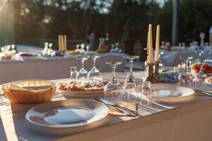 empty wine glasses on banquet served table in open air in rays of setting sun photo