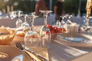 empty wine glasses on banquet served table in open air in rays of setting sun photo