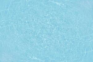 Blue water with ripples on the surface. Defocus blurred transparent blue colored clear calm water surface texture with splashes and bubbles. Water waves with shining pattern texture background. photo
