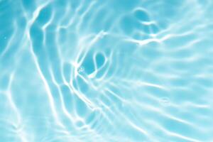 Blue water with ripples on the surface. Defocus blurred transparent blue colored clear calm water surface texture with splashes and bubbles. Water waves with shining pattern texture background. photo