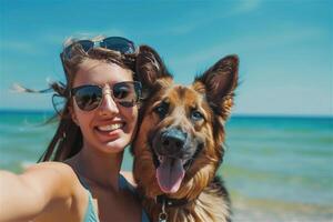Happy woman with a dog taking a selfie at the beach, summer day, sea background. Travelling with the dog concept. photo