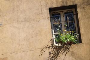 wall of a house with a window, flowers on the windowsill rustic style house facade photo