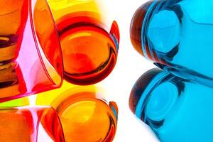 Close view of colorful glass cups in orange, yellow, and blue arranged in an abstract pattern on a white background. photo