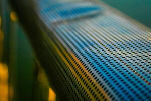 Close up of a perforated metal surface with a blurred background, showcasing the texture and pattern of the holes. photo