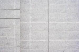 Close up of a tiled wall with a grid pattern, featuring light gray tiles and dark grout lines, as texture, background. photo