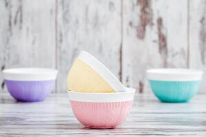 Colorful bowls with knitted patterns, stacked and arranged on a wooden surface with a rustic background. photo