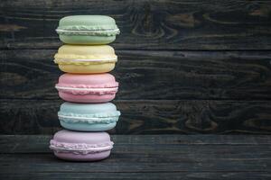 Colorful stack of macaroon shaped storage boxes displayed on a dark wooden background, with copy space. photo