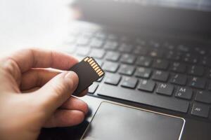 Memory card in hand, laptop, keyboard. flash drive information. data base. technology photo