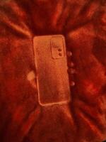 Phone mark on a fluffy blanket. Detailed print of a phone on a plush bedspread. Outline mark of a cellphone. photo