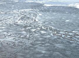 Broken ice of dark blue color on the river. Chunks of crushed ice on dark water. Abstract ice background. Blue background with cracks on the ice surface. Cracks of frozen water photo