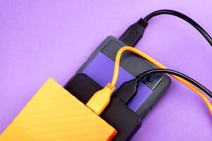 Multicolored external portable hard disk drives isolated on violet background photo