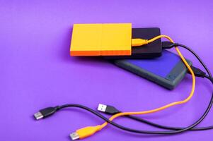 Multicolored external portable hard disk drives isolated on violet background photo