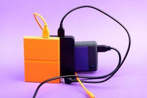 Multicolored external portable hard disk drives isolated on violet background photo