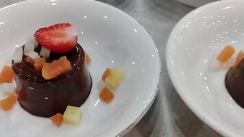 Point of view of many chocolate puddings with fruit toppings arranged on a white bowl. Sweet dessert, fresh and yummy video