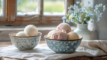Homemade vanilla and strawberry ice cream in floral ceramic bowls, bathed in natural window light, with a bouquet backdrop. photo