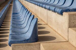 long rows of blue seats on a sports field stand photo