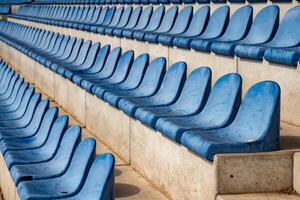 long rows of blue seats on a sports field stand photo