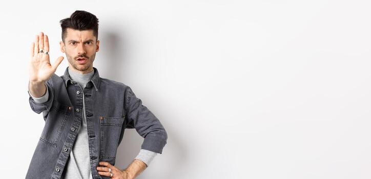 grave hombre contar a detener, prohibir alguna cosa y ceñudo, decir No, en pie disgustado con tramo fuera mano en contra blanco antecedentes foto