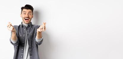 Excited romantic man showing hand hearts and smiling at camera, express love and affection, standing on white background photo
