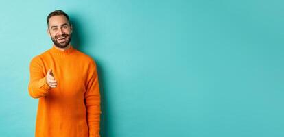 Friendly nice guy extend hand for handshake, greeting you and smiling, saying hello, standing over light blue background photo