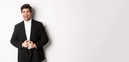 Concept of new year party, celebration and lifestyle. Portrait of handsome and confident man in suit, smiling pleased, feeling successful, standing over white background photo