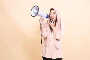 Asian woman looks at the camera with her right hand holding audio and holding a megaphone loudspeaker shouting cheerfully to announce the opening announcement. young beautiful for technology fashion photo