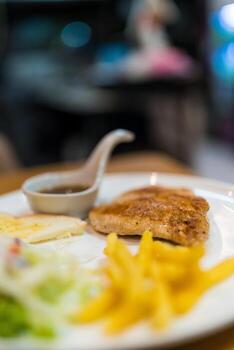 A la parrilla Cerdo filete servido con vegetales ensalada francés papas fritas y inmersión salsa foto