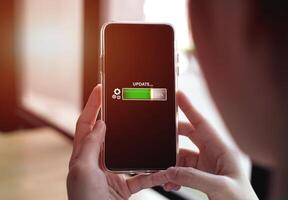 Improving modern technology, updating smartphone software with online networks. Showing screen on a smartphone with loading bar installing updates to improve system security. photo