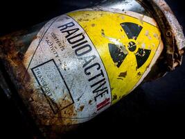 Radiation warning sign on the rusty and decay radioactive material container photo