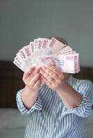 woman holds large stack of 200 Turkish lira bills in front of her, spreads it with a fan and shows it to the camera, a lot of money, but little value, high inflation in Turkey photo