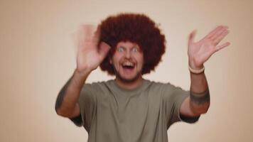 Bearded man smiling friendly at camera and waving hands gesturing hello or goodbye, welcoming video
