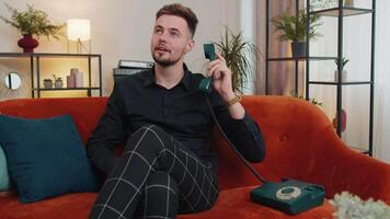 Man making retro telephone from 90s conversation with friends sitting call on couch at home in room video