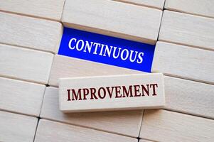 Top view of continuous improvement text on wooden blocks. Business strategy concept. photo