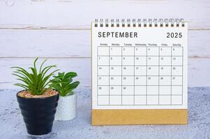 September 2025 calendar with white wooden wall background. New month and calendar concept photo