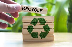 Hand placing wooden block with text recycle. Recycle concept with recycle symbol photo