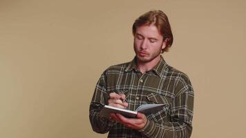 Thoughtful journalist man making notes, writing down thoughts with pen into notepad notebook diary video
