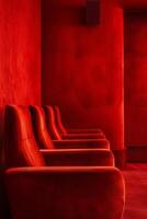 A row of red chairs in a red room photo