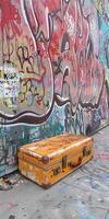 Yellow suitcase next to graffiti-covered wall photo