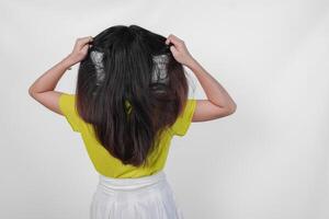 Back portrait of an Asian woman wearing a yellow t-shirt feeling stressed and having headache isolated by white background. photo