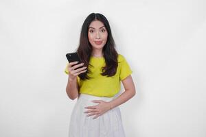 Hungry Asian woman is holding a cell phone and looking to the copy space upwards, thinking what to eat, isolated by white background. photo