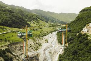 Kazbegi, Georgia - 7th july, 2024-aerial view cranes and bridge foundation pillars on construction site of new highway road project built by chinese builders.Avalanche bypass tunnel.Tbillisi - Lars photo