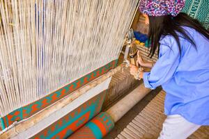 Meybod, Iran , 2022 - tourist try learn with machine making traditional iranian carpets photo